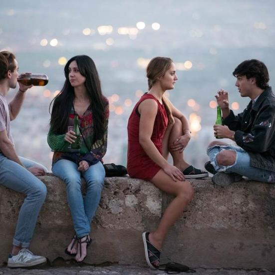 Fire unge mennesker drikker en øl og nyder udsigten